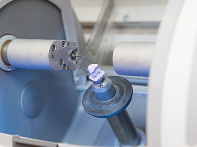 An industrial machine with mechanical components and a small blue object being processed on an assembly line.