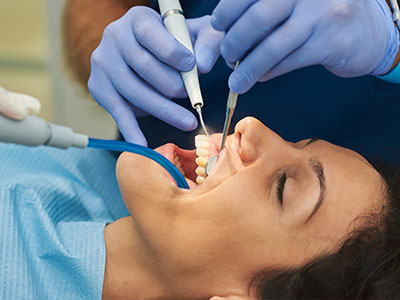 An individual receiving dental care with a dentist using specialized equipment.